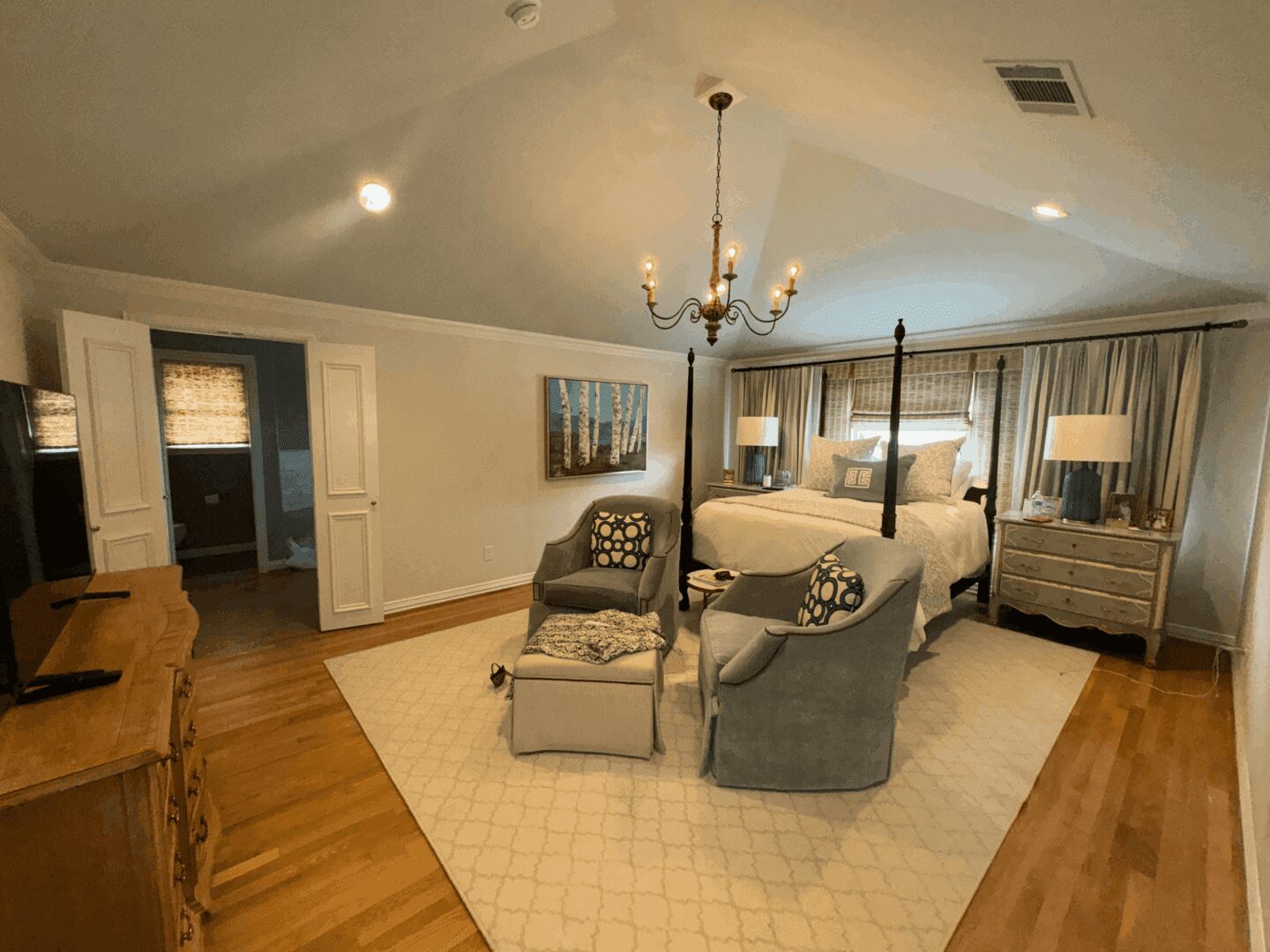 Spacious bedroom with elegant decor and chandelier.