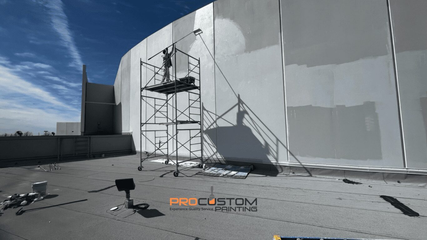 Person painting large white building wall.